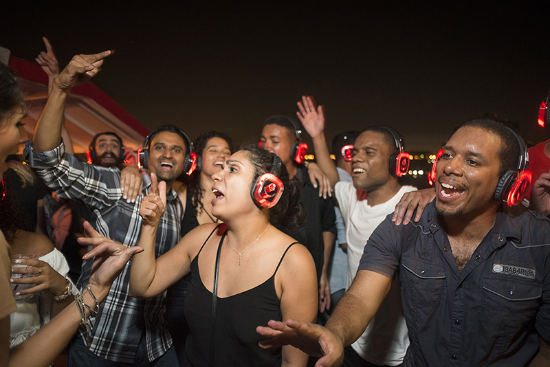 Group of people signing wearing glowing red headphones