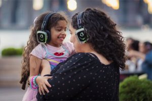 A mother holding her daughter wearing silent disco headphones