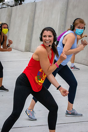 Fitness coach wearing headphones and a mic teaching zumba